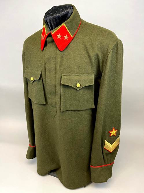 A green military uniform with red and gold patches

Description automatically generated