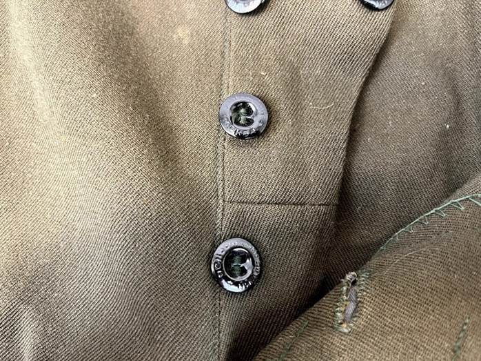 A close up of buttons on a green shirt

Description automatically generated