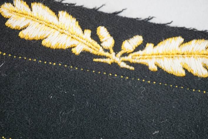 A close-up of a black fabric with a yellow embroidery

Description automatically generated