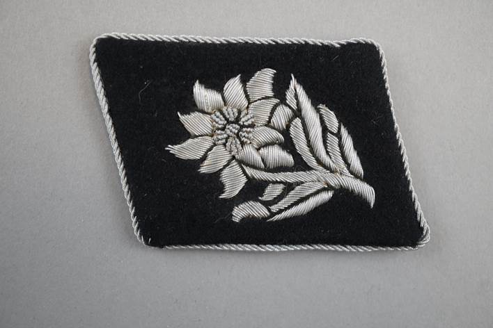 A black patch with white embroidery

Description automatically generated