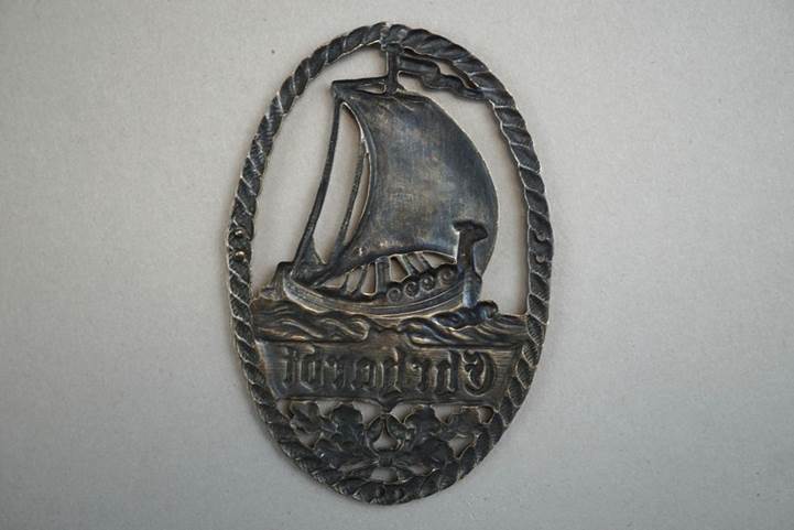 A metal plaque with a sailboat and text

Description automatically generated