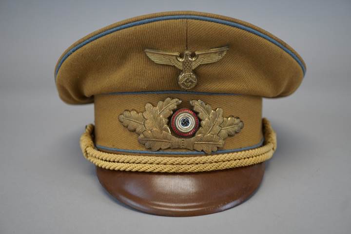 A brown hat with a gold emblem

Description automatically generated