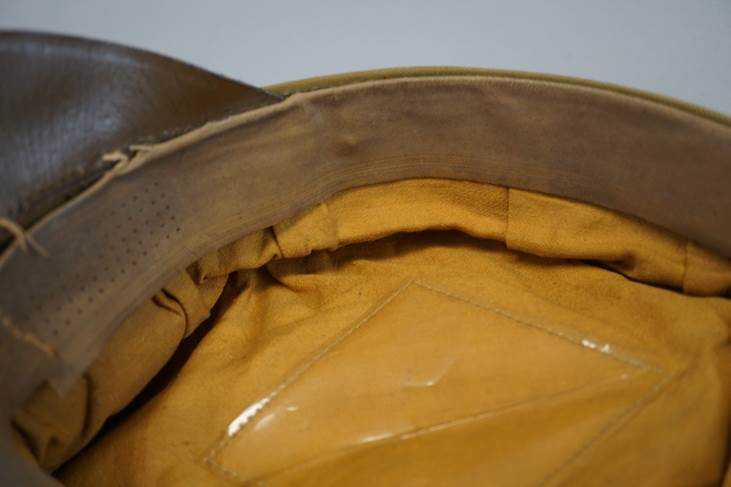 A brown leather hat with a yellow patch

Description automatically generated with medium confidence