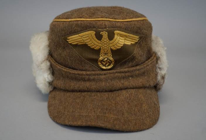 A brown hat with a gold eagle on it

Description automatically generated