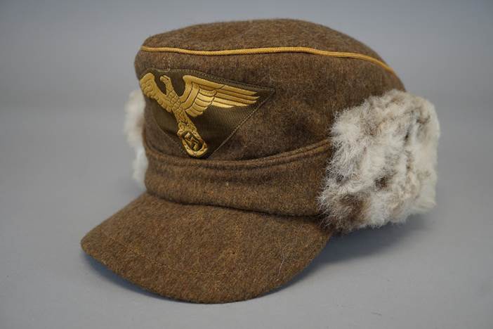 A brown hat with a gold eagle on it

Description automatically generated