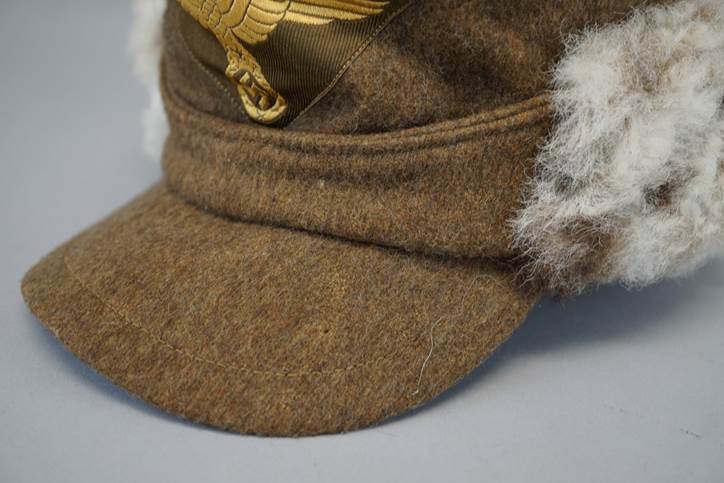 A brown hat with a gold eagle on it

Description automatically generated