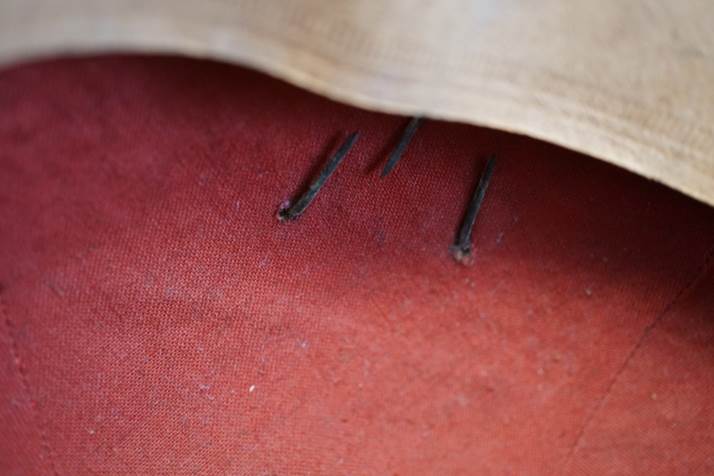 Close-up of a red fabric with nails

Description automatically generated