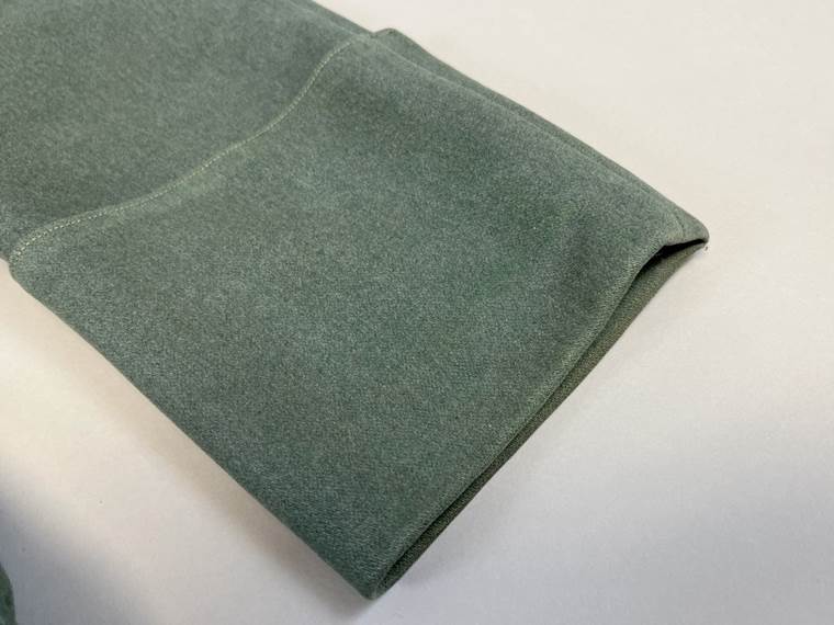 A folded green cloth on a white surface

AI-generated content may be incorrect.