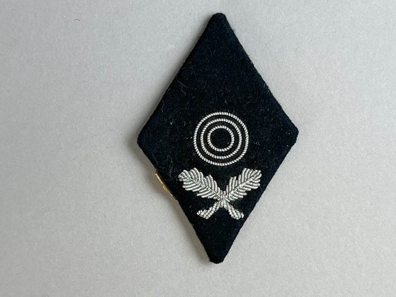 A black diamond shaped patch with silver and white embroidery

AI-generated content may be incorrect.