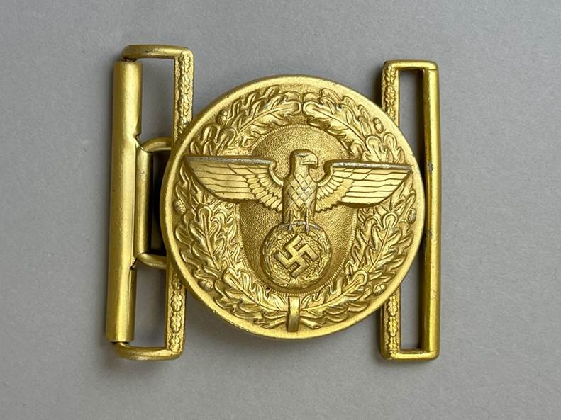 A gold belt buckle with a eagle and laurel wreath

AI-generated content may be incorrect.
