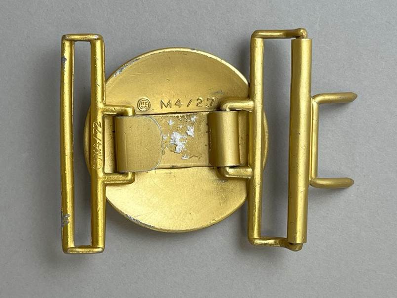 A gold belt buckle with two metal straps

AI-generated content may be incorrect.