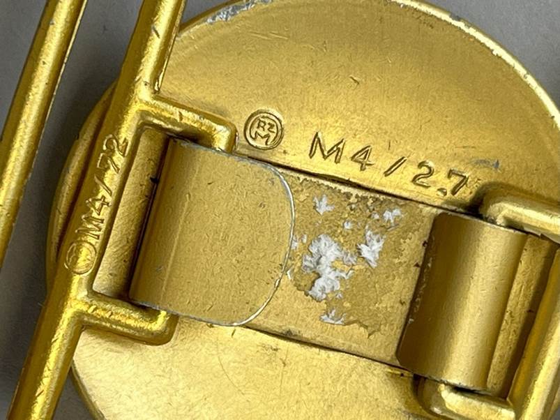 A close up of a gold belt buckle

AI-generated content may be incorrect.