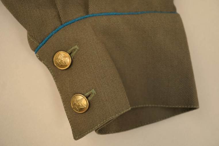 Close-up of a green uniform with buttons

AI-generated content may be incorrect.