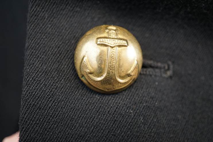 A gold anchor button on a black fabric

AI-generated content may be incorrect.