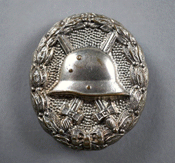 A metal badge with a helmet and cross

Description automatically generated