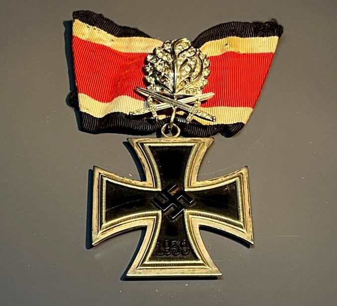 A gold and black cross with a red and black ribbon

AI-generated content may be incorrect.