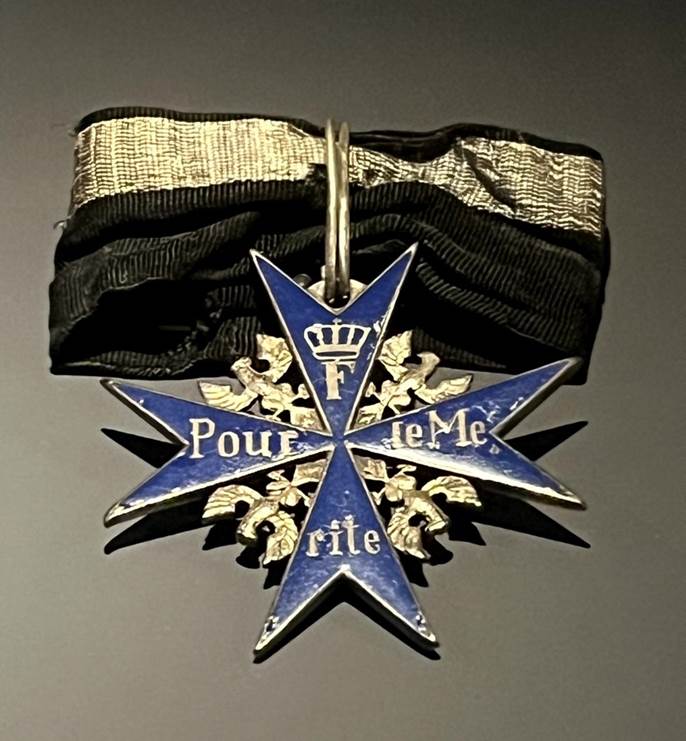 A blue and gold medal with a black ribbon

AI-generated content may be incorrect.